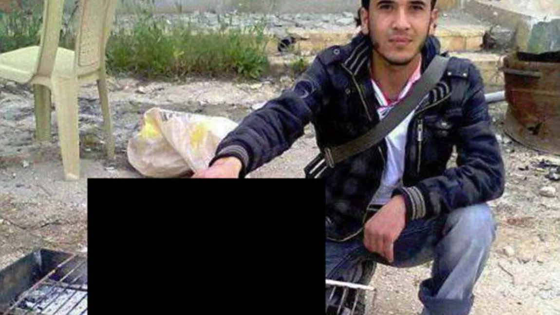 IMAGINEA BRUTALĂ A RĂZBOIULUI: Un rebel sirian ţine capul retezat al unui pilot pe grătarul încins