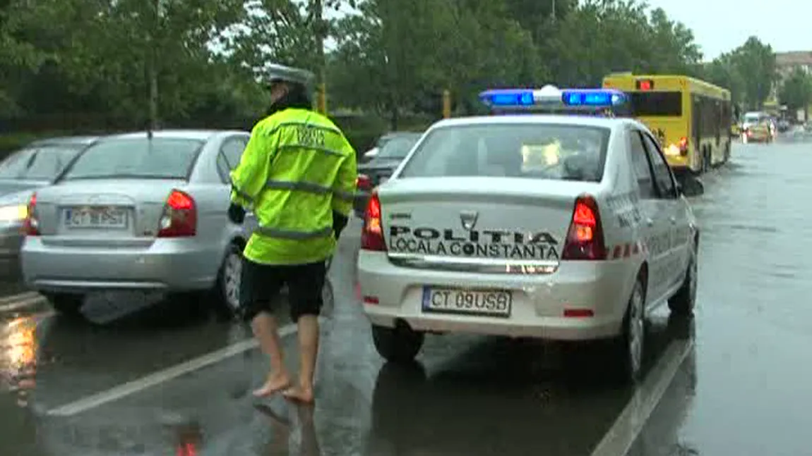 Imaginea zilei, după furtună. Un poliţist dirijează desculţ circulaţia VIDEO