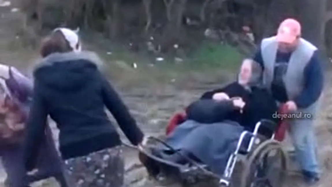O bătrână în scaun cu rotile, cărată de vecini la ambulanţa rămasă în noroi VIDEO