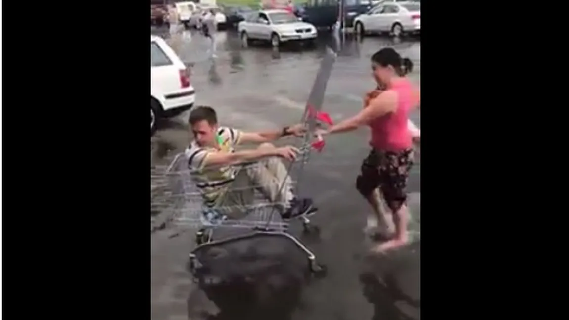 Soţul în căruţ, soţia cu copilul în braţe prin apă VIDEO