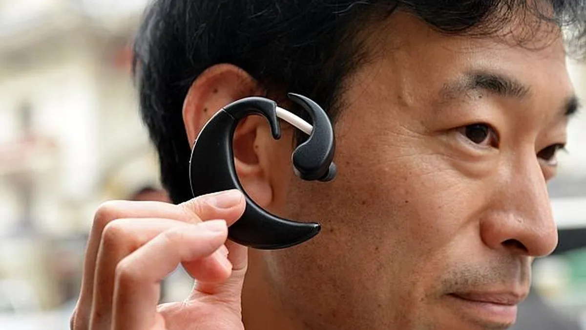 Japonezii lucreaza la un mini-calculator portabil la ureche