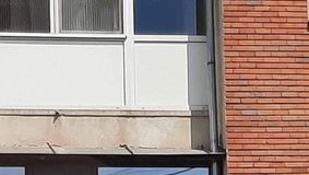 Fotografia care a devenit virală în România. O femeie îmbrăcată provocator șterge geamul unui apartament, situat deasupra unei instituții publice