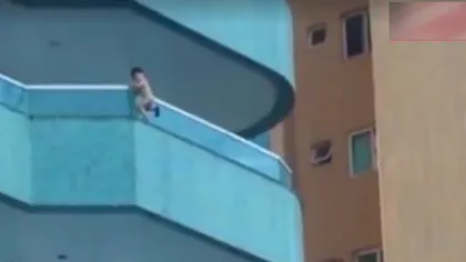 Imagini INCREDIBILE: Un bebeluş se BALANSEAZĂ pe marginea EXTERIOARĂ a unui BALCON la 20 de metri în aer VIDEO