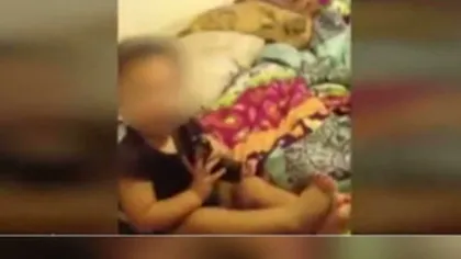 ŞOCANT: Copil de un an, filmat cu arma în gură de părinţi VIDEO