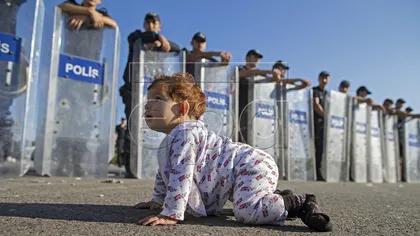 IMAGINEA ZILEI: Un bebeluş sirian se joacă în faţa cordonului de poliţie, în Turcia FOTO