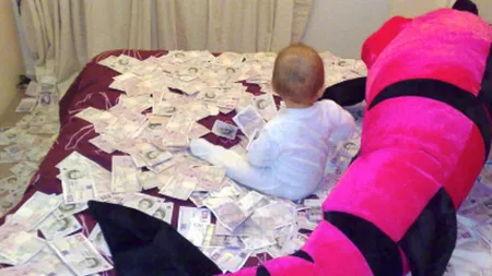 Bebeluş român, fotografiat pe o grămadă de bani furaţi