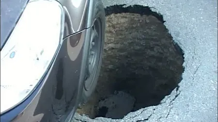 Asfalt surpat sub o maşină aflată în trafic. Autoturismul a rămas blocat într-o gropă imensă VIDEO