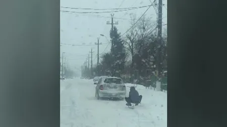 Distracţie periculoasă: Un bărbat s-a dat cu sania trasă de o maşină pe drum