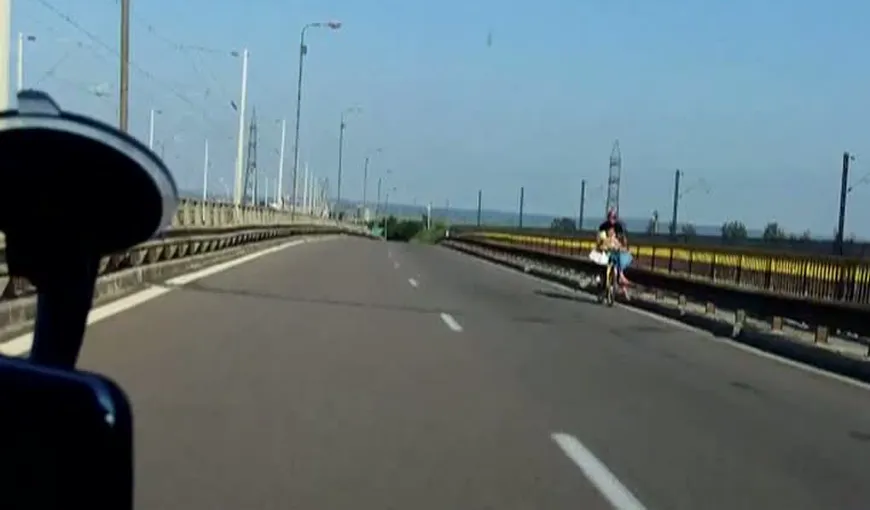 PĂRINŢI INCONŞTIENŢI: Surprinşi cu bicicleta pe autostradă şi cu bebeluşul în braţe VIDEO