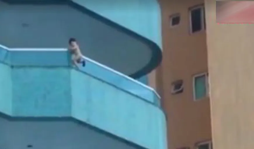 Imagini INCREDIBILE: Un bebeluş se BALANSEAZĂ pe marginea EXTERIOARĂ a unui BALCON la 20 de metri în aer VIDEO