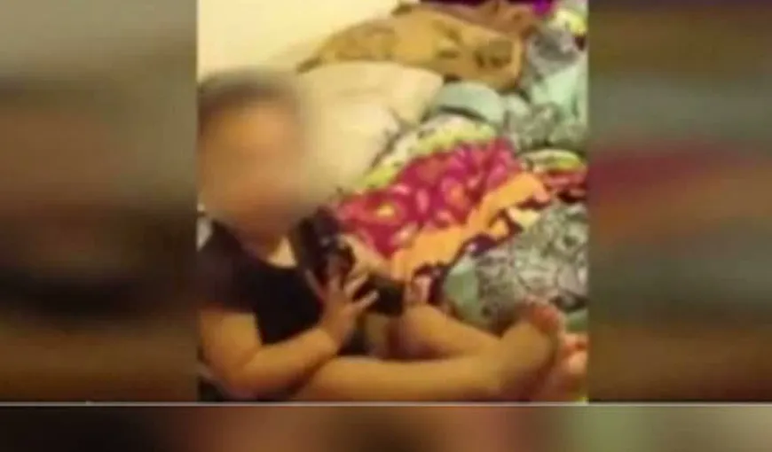 ŞOCANT: Copil de un an, filmat cu arma în gură de părinţi VIDEO