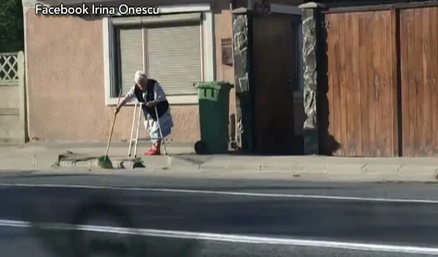 Imagini virale pe Facebook, o bătrână sprijinită de cadru mătură trotuarul VIDEO