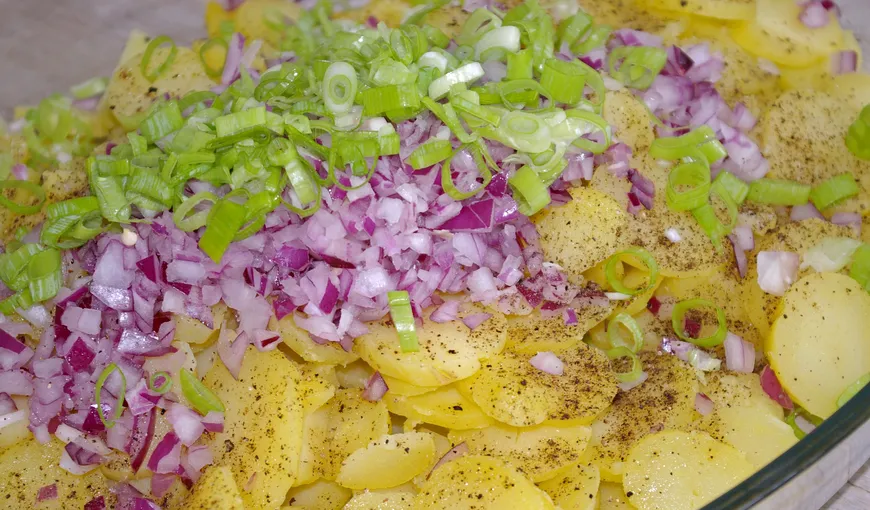Cartofi copţi, cu brânză, pe un pat de salată verde